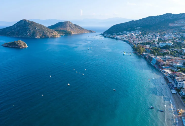 View of Tolo beach, trees, turquoise waters and the islets of Tolo in the background